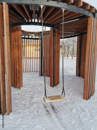 Wooden gazebo iwith swings in january park