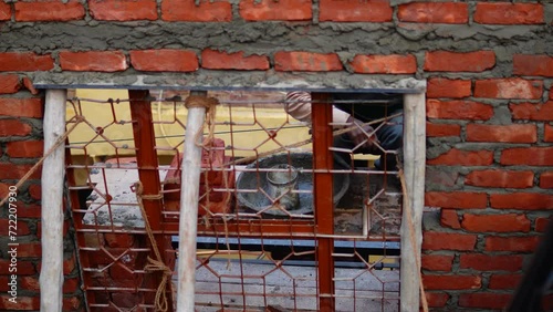 Through an underconstructed window, Loborer seen placing Bricks on Shelf photo