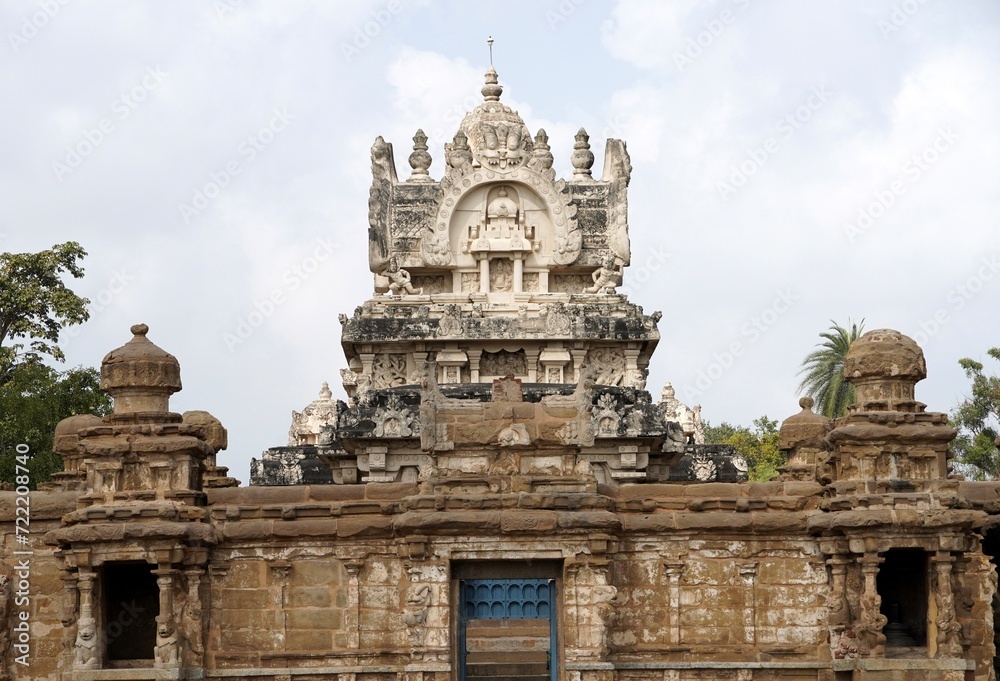 Facade of ancient Kailasanathar temple. Historic Hindu Temple tower with sandstone carvings against cloudy background.