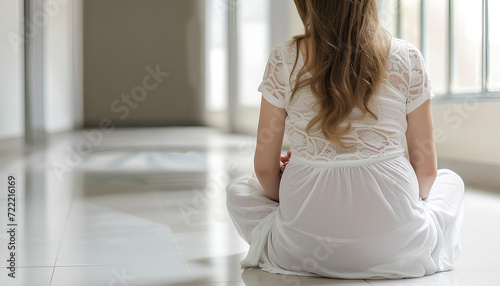 Mid section of pregnant woman sitting in white hospital corridor