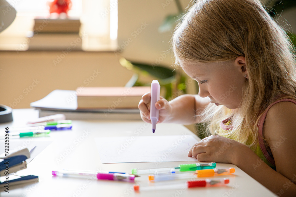 Little child girl draws with a marker while sitting at the table Little child girl draws with a marker while sitting at the table