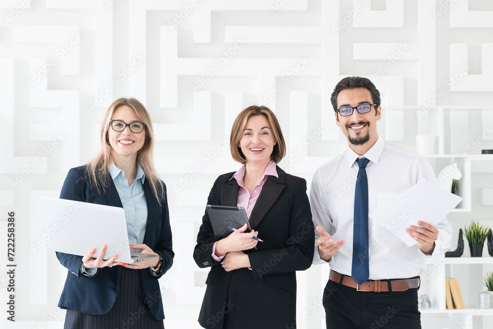 Successful business people standing in the bright office and smiling at camera Successful business people standing in the bright office and smiling at camera