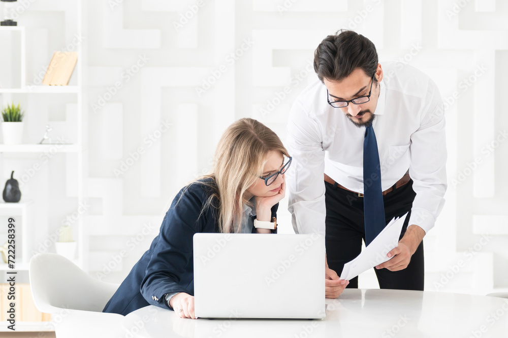 Two concentrated business people working at the desk on laptop in the office Two concentrated business people working at the desk on laptop in the office