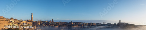 Foggy sunrise in Siena, Italy, panorama with Torre del Mangia and the Church of Santa Maria dei Servi © Brue