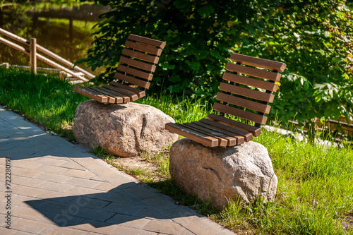 Original design infrastructure object in the city park. Wooden benches on large stones. A pedestrian path leads through the park. Smiltene Old Park, Latvia. photo