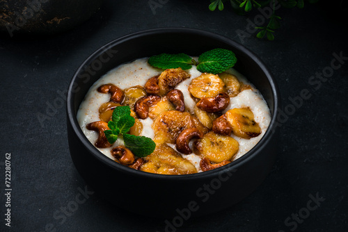 Breakfast boiled oatmeal with fried bananas, cashews and mint.