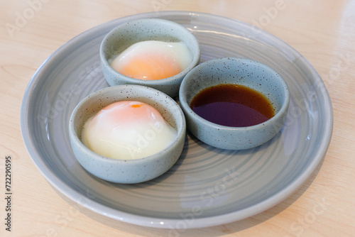 Soft-boiled eggs or Onsen tamago eggs in traditional Japanese served with shoyu soy sauce on wooden background