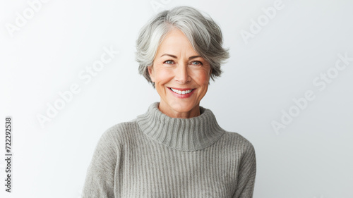 Portrait of smiling middle aged woman. Portrait of attractive brunette woman standing and smiling at camera isolated on grey background. 