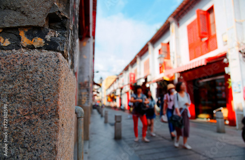 Tourists walking on the Street of Happiness (Rua da Felicidade), which is a bygone red light district in Macau, China, and flanked by traditional Chinese houses with conspicuous red doors and windows photo