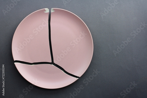 A broken pink ceramic plate on a gray background. view from above. The concept of diet, old things