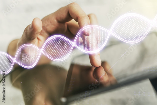 Double exposure of creative DNA hologram and finger clicks on a digital tablet on background. Bio Engineering and DNA Research concept