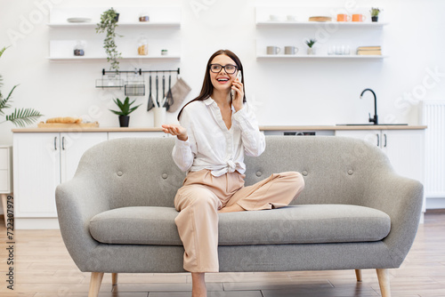 Free Download Beautiful woman relaxing on sofa at home and using modern smartphone for talking with family. Caucasian brunette using modern devices enjoying break from work for business negotiations on weekend. - GFXLoad