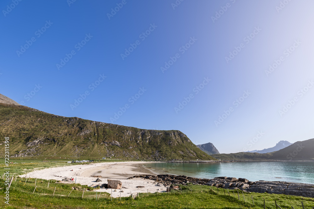 The serene Haukland Beach in the Lofoten Islands, Norway, with its distinct turquoise waters and curving shoreline against a mountainous backdrop The serene Haukland Beach in the Lofoten Islands, Norway, with its distinct turquoise waters and curving shoreline against a mountainous backdrop