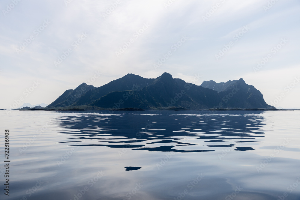 A serene panorama of the Lofoten Islands, with glassy waters reflecting the jagged peaks under a soft, diffused light