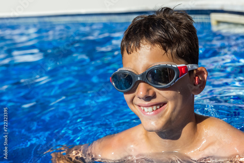 Little boy getting ready to swim in the pool, having ear plugs and goggles. Summer break vacation. © Mediteraneo