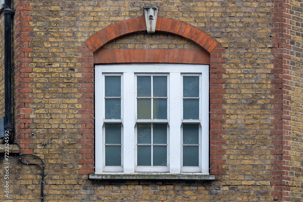 classic white windows of typical London architecture with red brick wall, uk