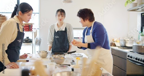 Cooking class, women and learning to cook, chef and japanese food in kitchen, professional and skill. Restaurant, teaching and course for culinary skills, working together and aprons for cleanliness photo