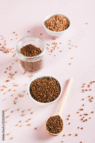 Raw buckwheat tea in a bowl and wooden spoon and buckwheat on the table vertical view