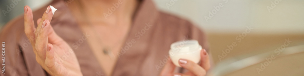Header with hands of woman applying moisturizing face cream Header with hands of woman applying moisturizing face cream