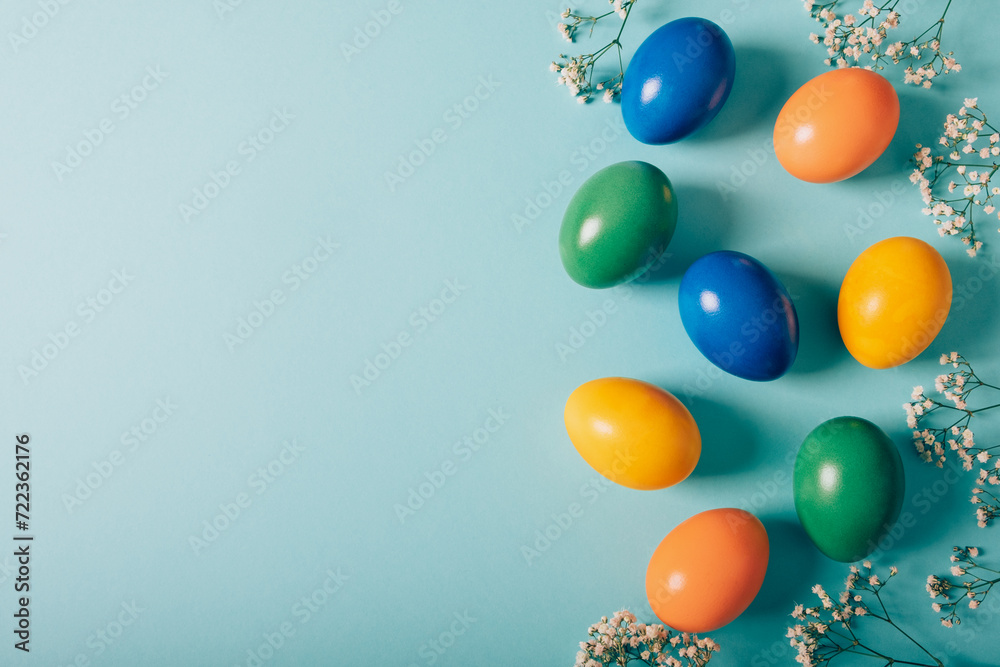 Colorful naturally dyed Easter eggs and spring flowers on pastel azure background, top view, flat lay style. Copy space for text. Colorful naturally dyed Easter eggs and spring flowers on pastel azure background, top view, flat lay style. Copy space for text.