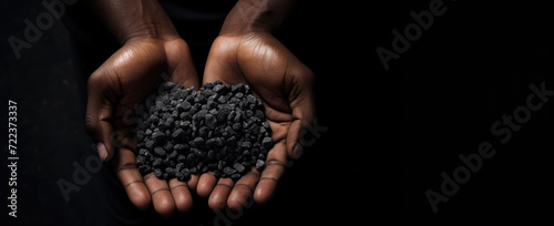 Slavery in mining. African hands holding coltan grains over dark background with copy space