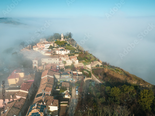Italy, January 28, 2024: aerial view of the medieval village of Fiorenzuola di Focara immersed in fog. We are in the San Bartolo park near Pesaro in the Marche region photo