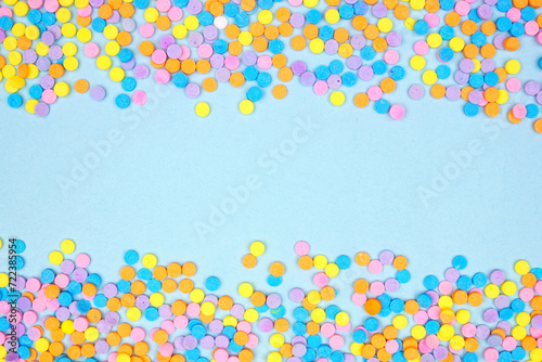 Colorful candy sprinkles double border. Above view on a blue banner background. Pastel Easter color theme. Copy space.