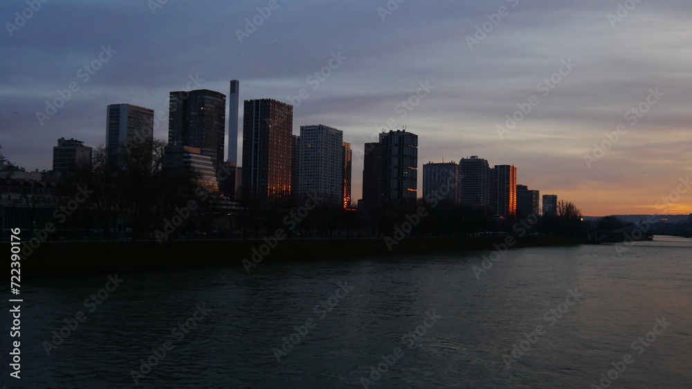 Balade au bord de la Seine, pendant le couché du Soleil, ciel sombre, façade éclairé par des lumières, péniche en circulation, personne discutant au bord de la Seine, balade urbaine, détente de week