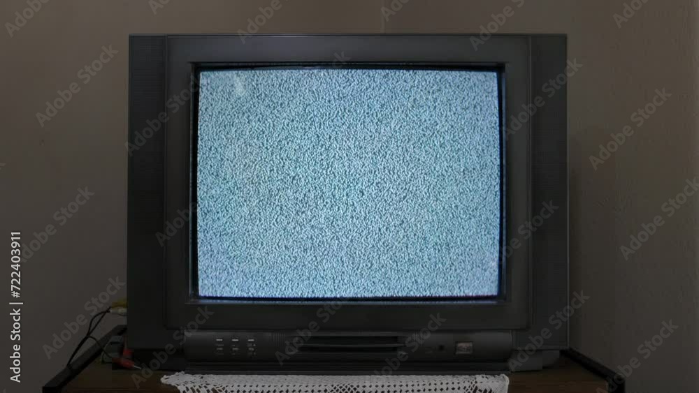 An old CRT TV sitting on a shelf, with no signal, displays static white noise