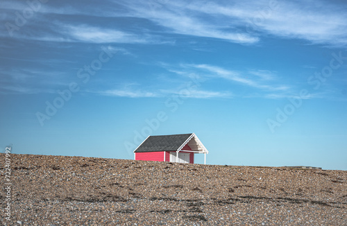 Fototapeta Naklejka Na Ścianę i Meble -  Single little cabin hiding behind pebble dune on a beach of Lancin, West Sussex, UK