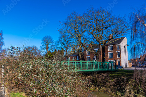 A view towards a footbridge over the River Welland opposite Welland Place in the centre of Spalding, Lincolnshire on a bright sunny day