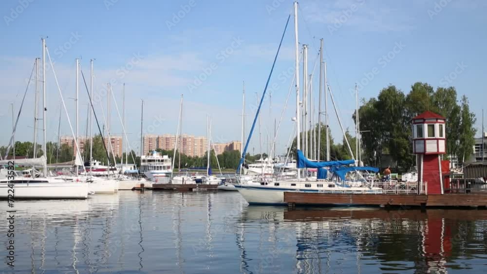 White yachts stand in berth near apartment buildings at summer day. White yachts stand in berth near apartment buildings at summer day.