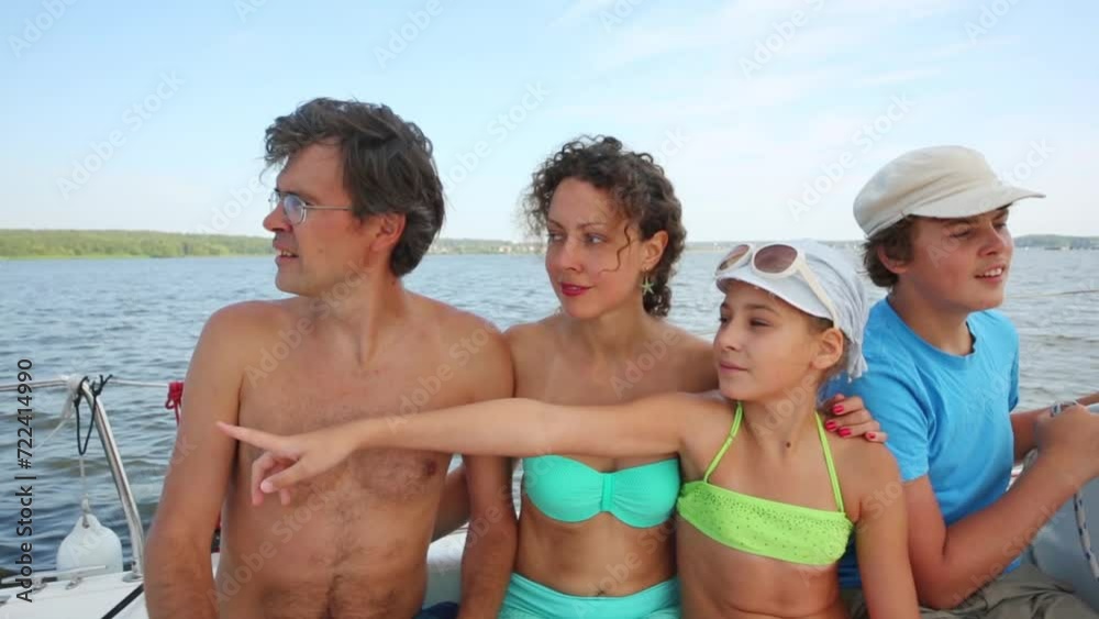 Family of man, woman, girl, boy sit together on stern of swimming yacht Family of man, woman, girl, boy sit together on stern of swimming yacht