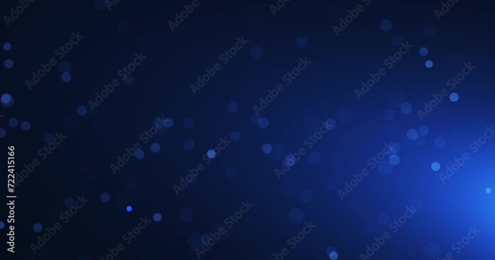 Slow flying blurred particles on blue background. Dust in the air in the rays of light. Seamless looping animation.