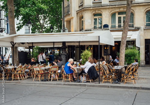Typical view of the Parisian street with tables of brasserie (cafe) in Paris, France. Cozy cityscape of Paris. Architecture and landmarks of Paris.