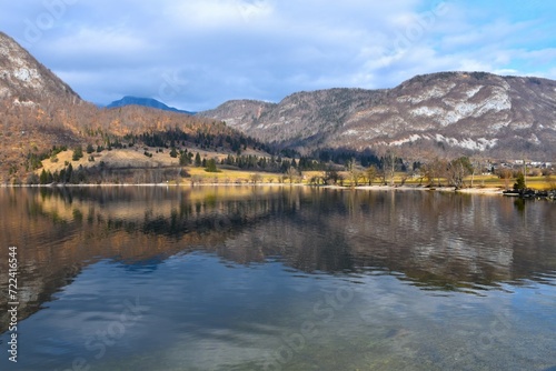 View of Bohinj lake and forest covered hills and mountains and reflection in the water in Slovenia