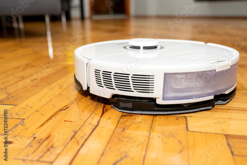 robot vacuum cleaner in modern smart home, robotic vacuum cleaner on wooden or laminate or parquet floor, cleaning dust on tile floors. Modern smart cleaning technology housekeeping.