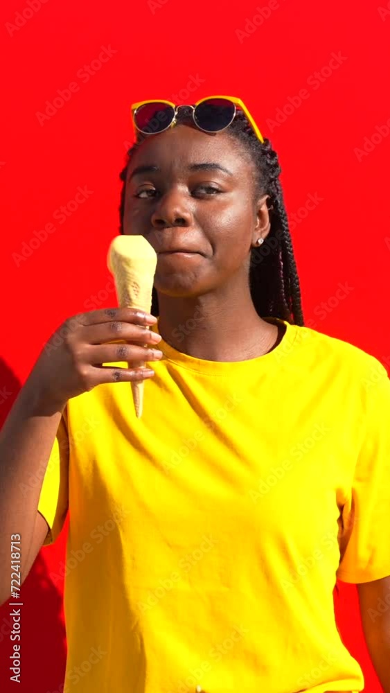 Cool stylish young african woman licking an ice cream in red background Cool stylish young african woman licking an ice cream in red background