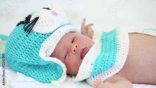 Little cute newborn baby is laying in knitting cat costume on blanket. photo
