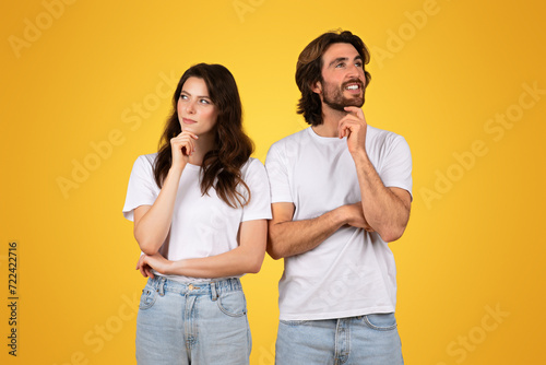 Thoughtful couple in white t-shirts, with the man and woman looking upwards with hand on chin