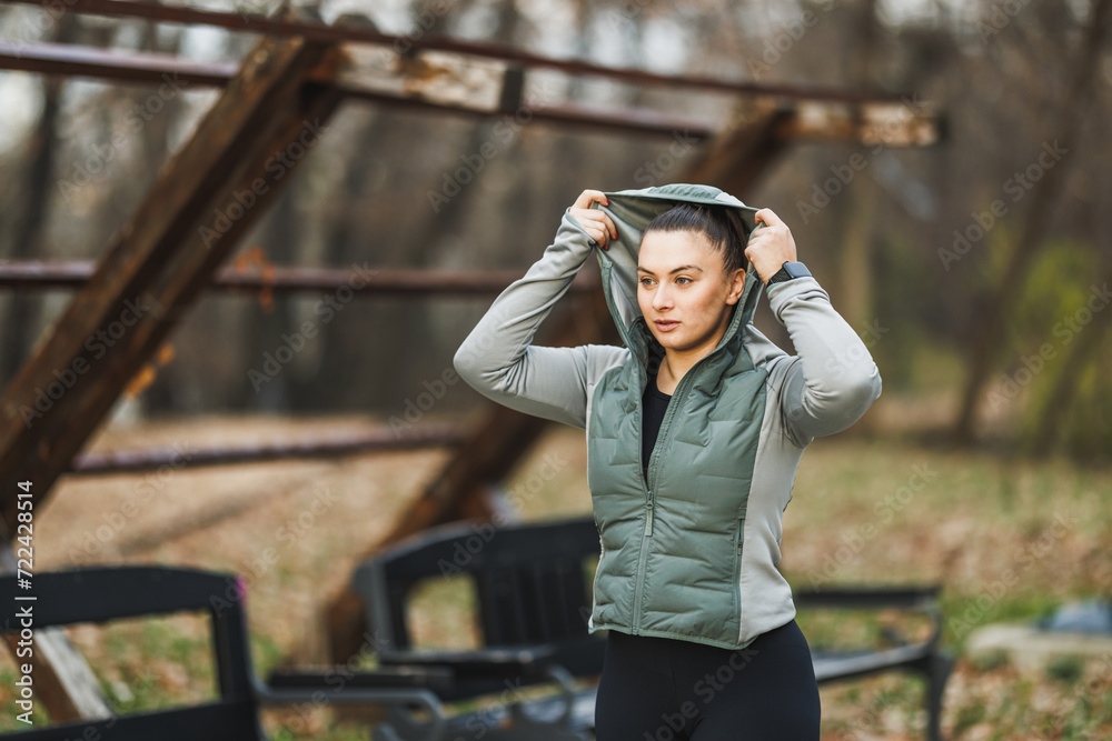 Woman in Green Jacket Holding Hoodie Over Head After Training Outdoor