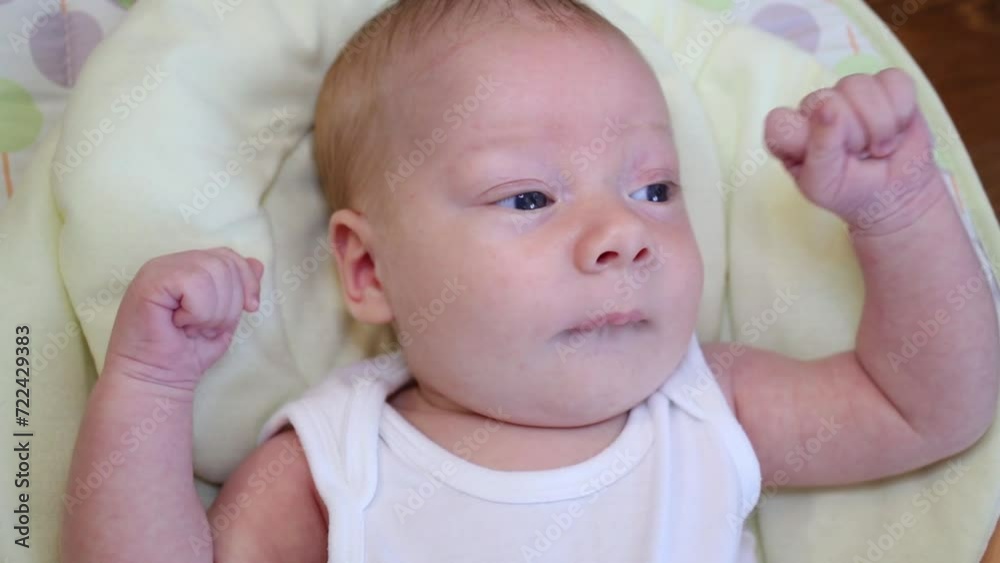 Baby boy in a white shirt lying in a cradle close-up