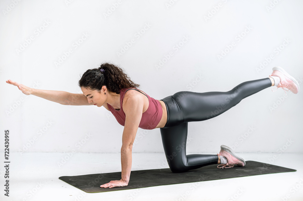 Woman practicing yoga, standing in bird dog pose on mat in studio Woman practicing yoga, standing in bird dog pose on mat in studio