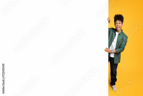 Excited african american guy standing next to advertising board