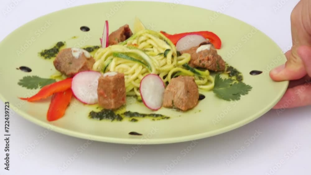 Man takes and puts back a plate of spaghetti, vegetables, herbs and meat Man takes and puts back a plate of spaghetti, vegetables, herbs and meat