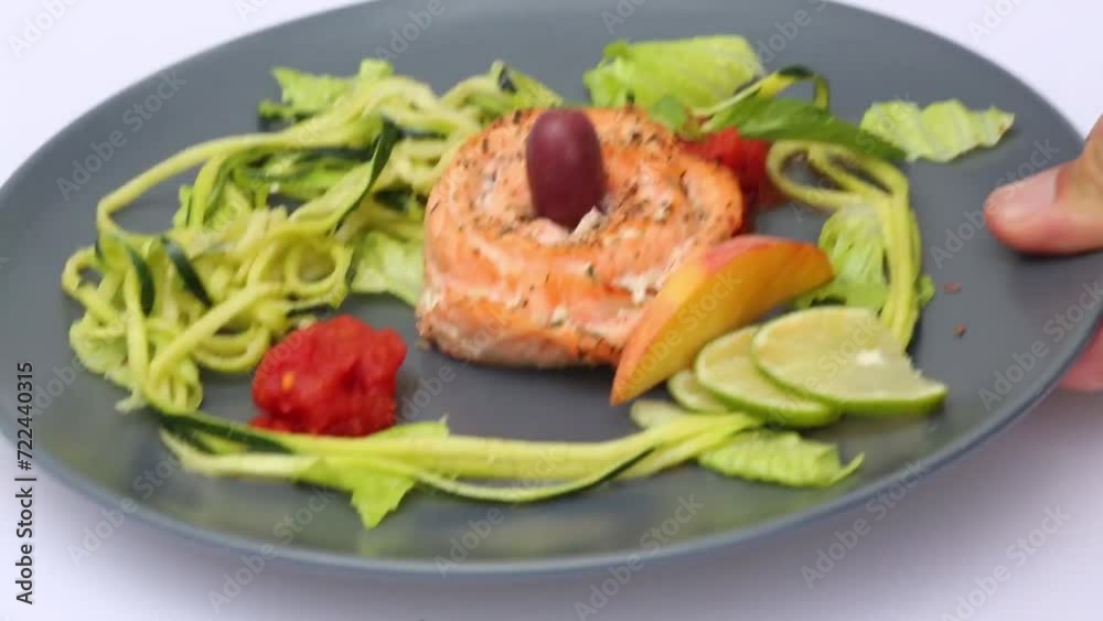 Man takes and puts back plate with fish roll with cucumber, lime and lettuce Man takes and puts back plate with fish roll with cucumber, lime and lettuce
