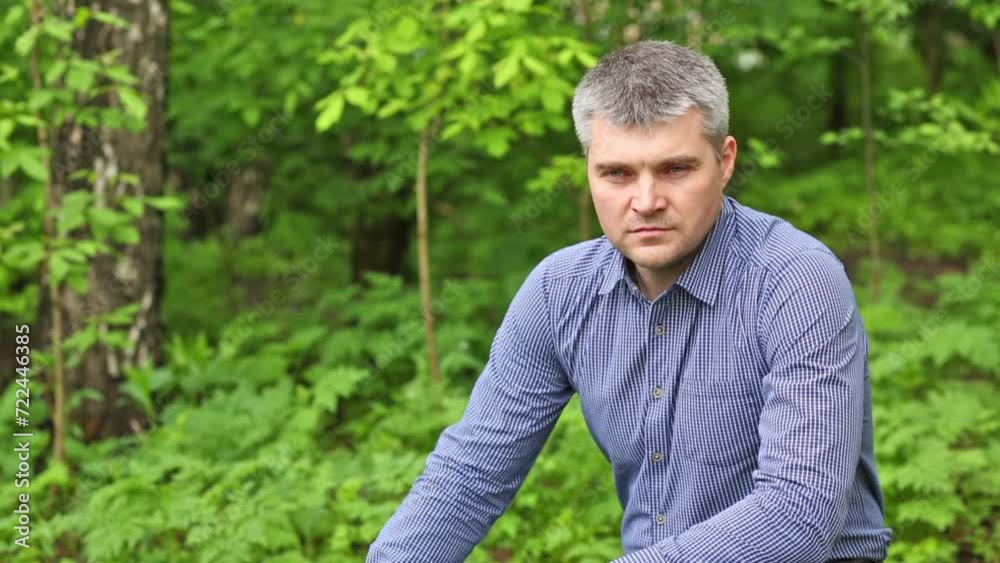 Man with gray hair in striped shirt sit and turn head in park. Man with gray hair in striped shirt sit and turn head in park.