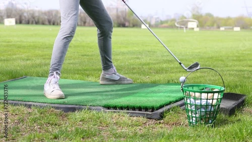 Little girl is swinging cammock and than hit the ball for golf on a field. photo