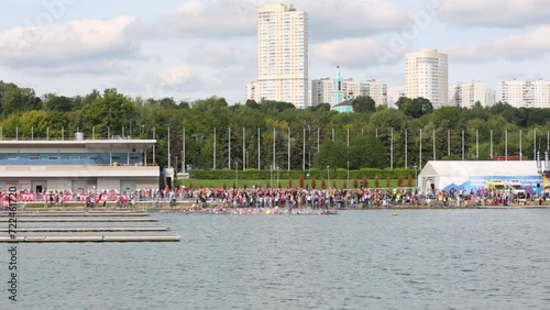 Large group of people begins to swim for the canoe during a triathlon photo