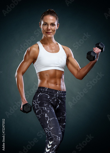 Fit strong woman lifting weights. Working out with dumbbells